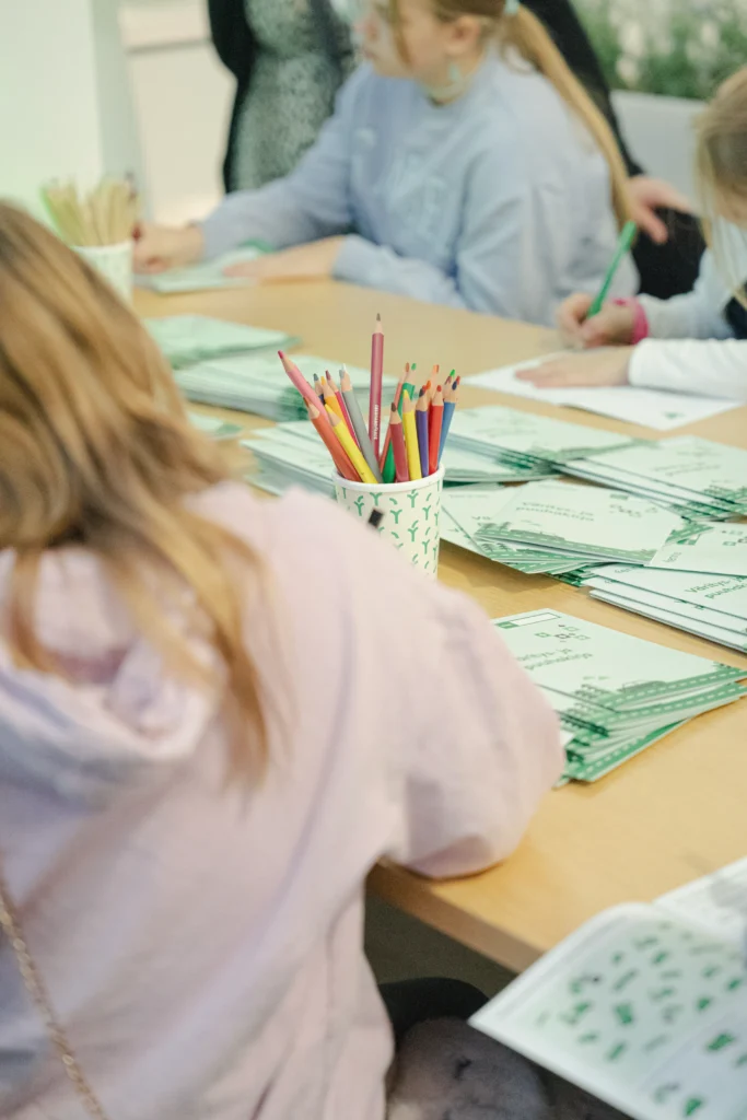 Lapset piirtää värikynillä Fennia-puuhakirjoihin
